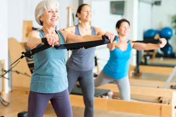 Toning Arms After 60: Empowering Womens Fitness Through Effective Weight Training 2 older woman doing weight training Buxton and resistance in the gym to tone upper arms