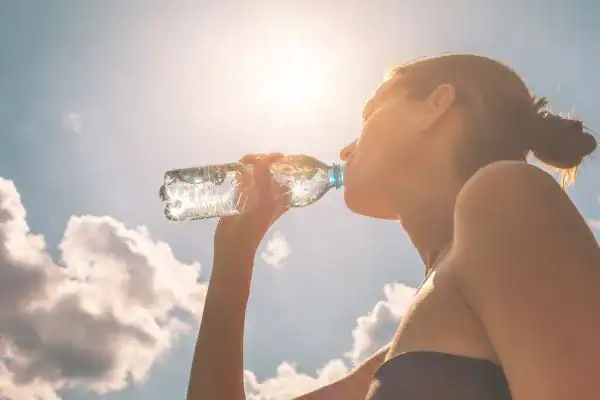 Hydration: The Secret Ingredient for a Toned Stomach and Enhanced Fitness 3 Image of woman drinking water to hydrate Buxton after run.