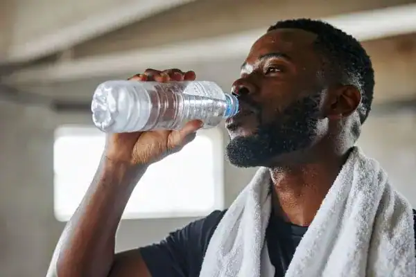 Image of man drinking water to improve hydration Buxton after work out.